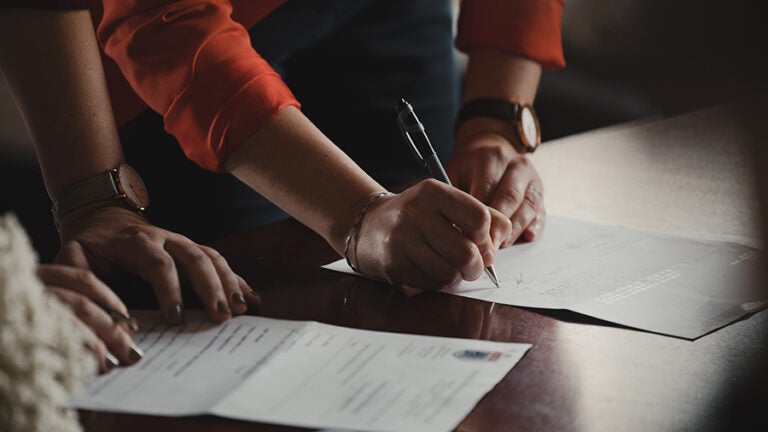 two people writing on papers on table