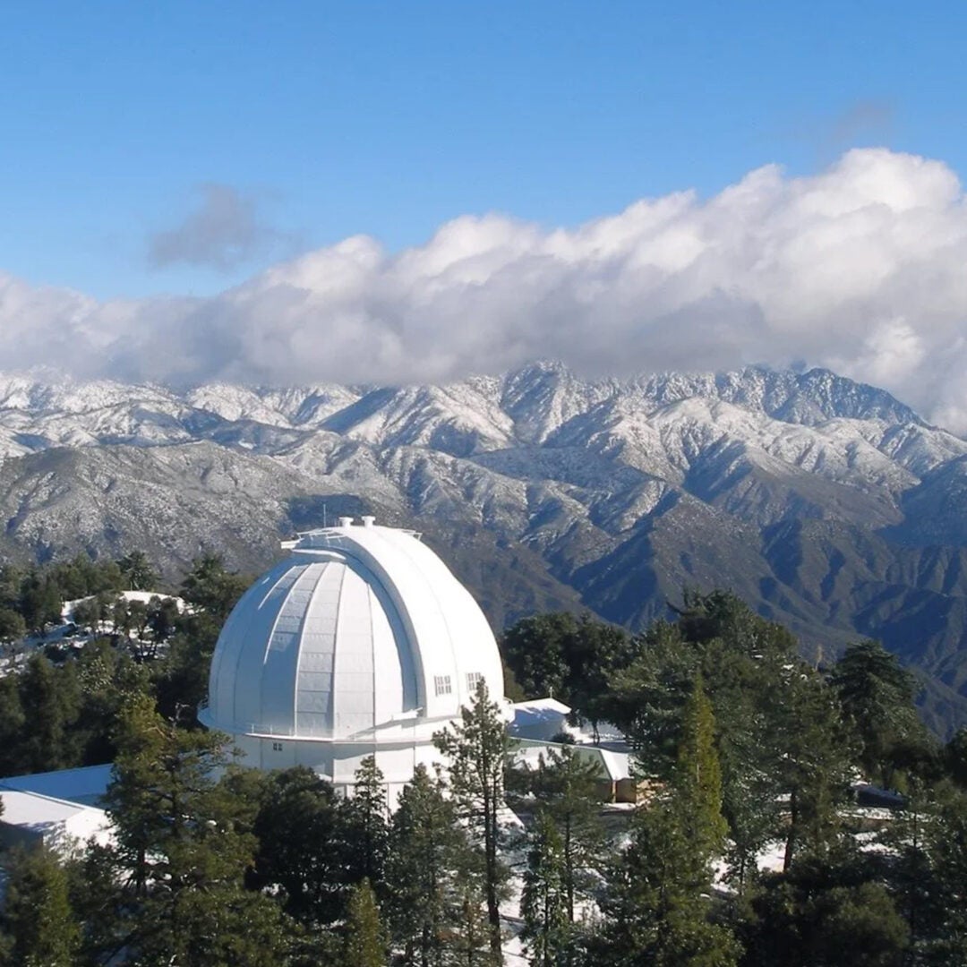 Mount Wilson Observatory with mountain range in the background and clouds