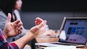 people talking in front of laptop, focus on the hands